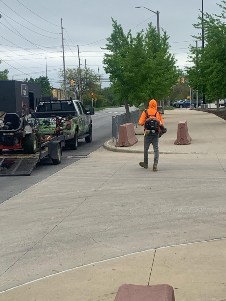 A man in an orange jacket walking down the street.