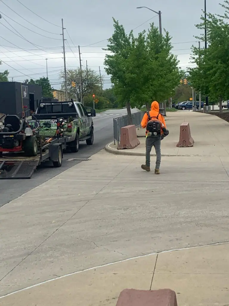 A man in an orange jacket walking down the street.